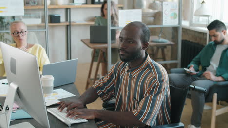 Black-Businessman-with-Disability-Typing-on-Computer-in-Office